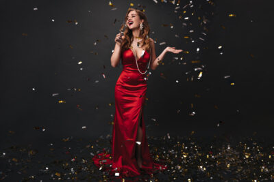 full-length-portrait-woman-red-dress-drinking-champagne-black-background